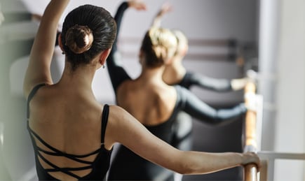 Ballerinas practicing using barre in a dance studio